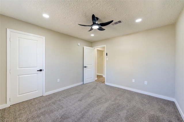 unfurnished bedroom with ceiling fan, carpet, and a textured ceiling