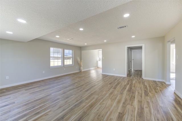 spare room featuring a textured ceiling and light hardwood / wood-style flooring