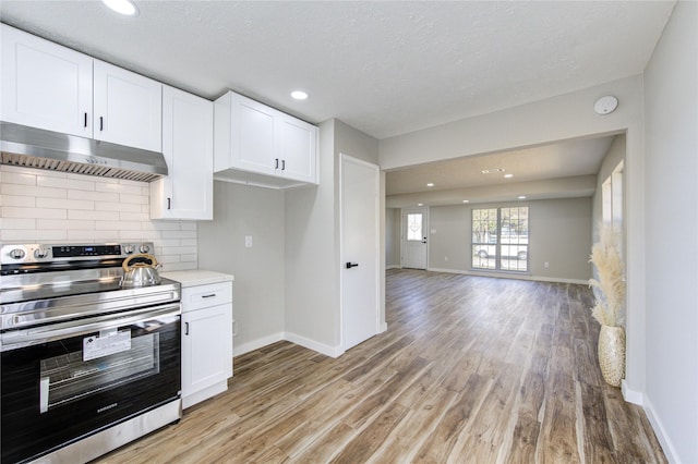 kitchen featuring electric range, white cabinets, light wood-type flooring, and backsplash