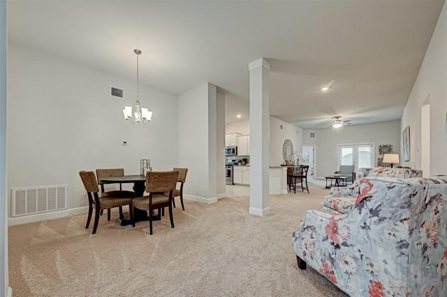 dining area with ceiling fan with notable chandelier and light colored carpet