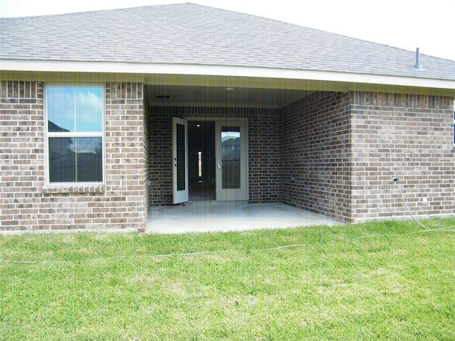 view of exterior entry with a yard and a patio