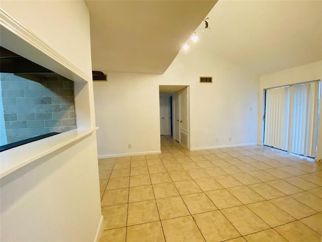 empty room featuring light tile patterned floors and high vaulted ceiling