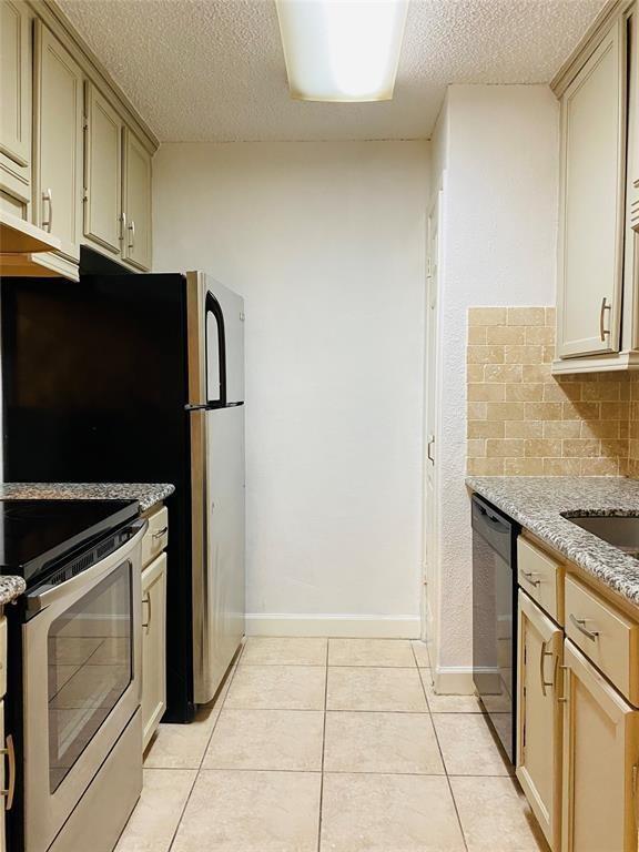 kitchen featuring stove, black dishwasher, cream cabinets, and light tile patterned floors