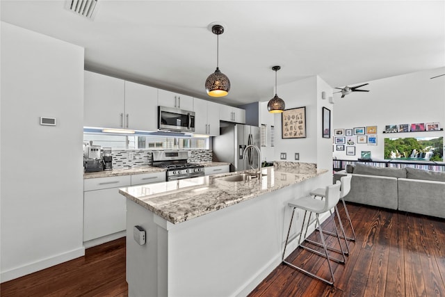 kitchen with white cabinets, a kitchen breakfast bar, sink, decorative light fixtures, and stainless steel appliances