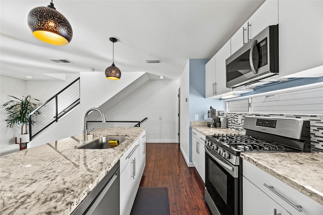 kitchen with backsplash, stainless steel appliances, sink, white cabinetry, and hanging light fixtures