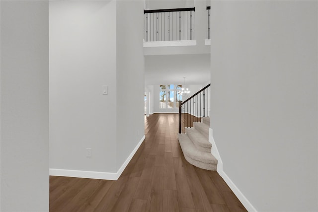 hall featuring hardwood / wood-style flooring, a notable chandelier, and a high ceiling