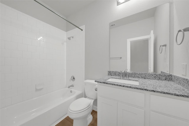 full bathroom with hardwood / wood-style flooring, vanity, tiled shower / bath combo, and toilet