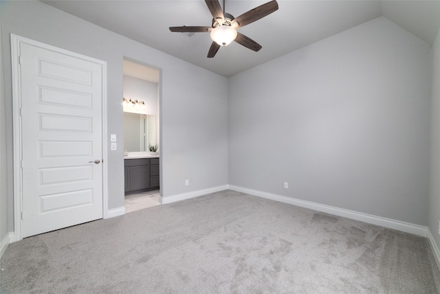 unfurnished bedroom featuring ceiling fan, light colored carpet, lofted ceiling, and ensuite bath