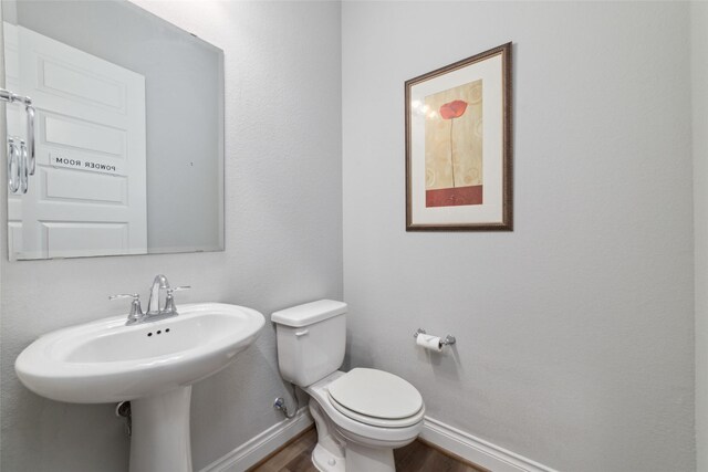 bathroom with hardwood / wood-style flooring and toilet