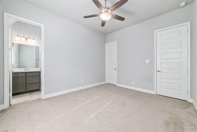 unfurnished bedroom with ensuite bathroom, sink, light colored carpet, and ceiling fan