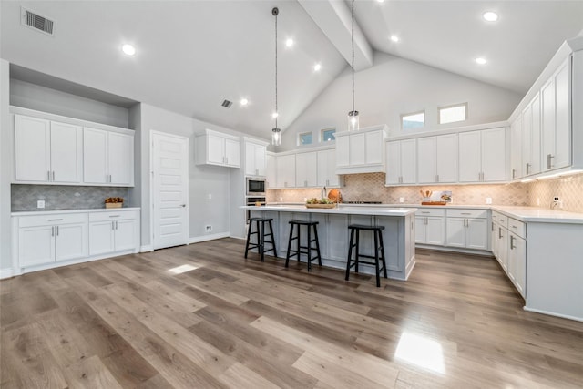 kitchen featuring an island with sink, white cabinets, and light hardwood / wood-style floors