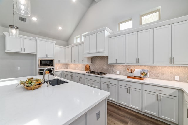 kitchen with sink, white cabinetry, decorative light fixtures, vaulted ceiling, and appliances with stainless steel finishes