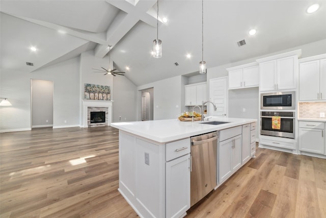 kitchen featuring sink, a kitchen island with sink, hanging light fixtures, stainless steel appliances, and white cabinets