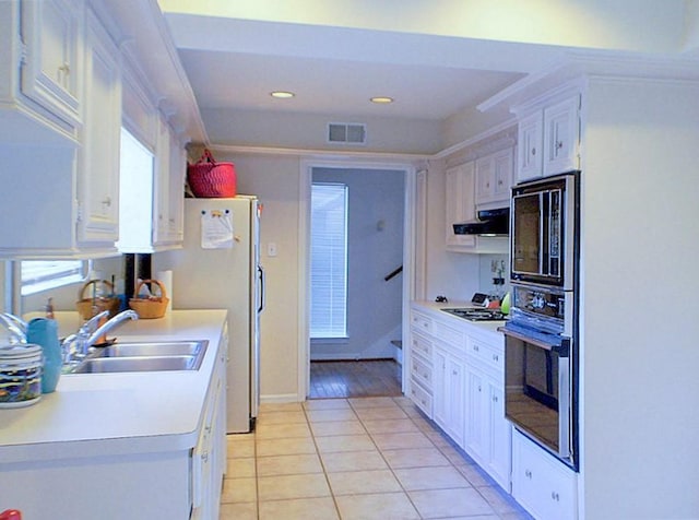 kitchen featuring gas cooktop, wall oven, sink, light tile patterned floors, and white cabinets