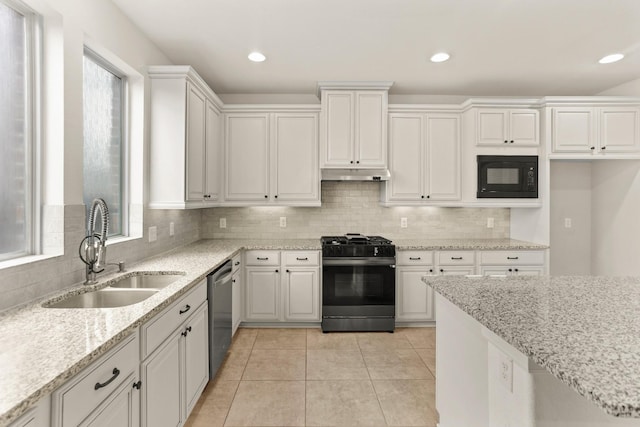 kitchen with white cabinetry, sink, light stone counters, light tile patterned floors, and black appliances