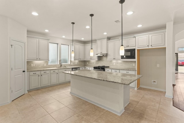 kitchen featuring light stone countertops, black appliances, decorative light fixtures, white cabinets, and a kitchen island