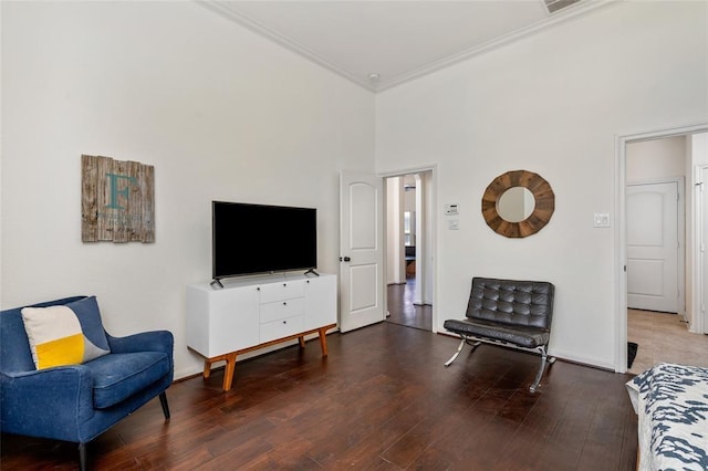 living room featuring hardwood / wood-style flooring, ornamental molding, and a towering ceiling