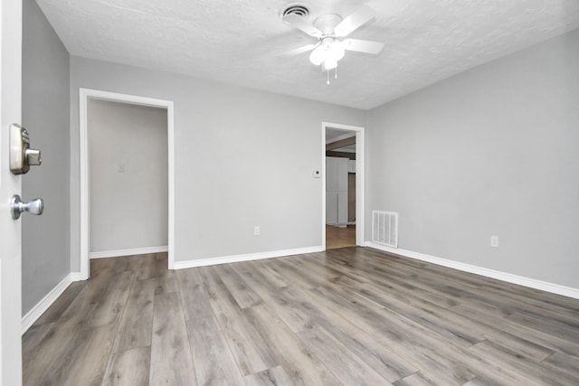 unfurnished room with a textured ceiling, light hardwood / wood-style floors, and ceiling fan