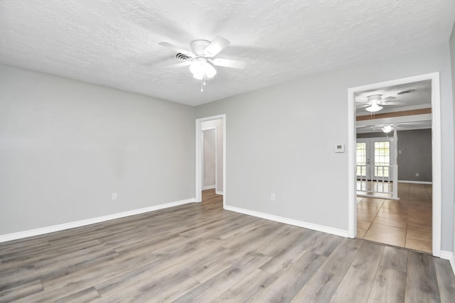 unfurnished room with ceiling fan, light hardwood / wood-style floors, a textured ceiling, and french doors