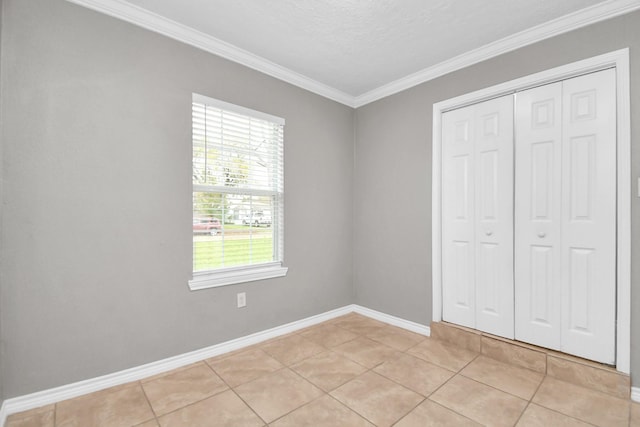 unfurnished bedroom with light tile patterned floors, a textured ceiling, a closet, and ornamental molding