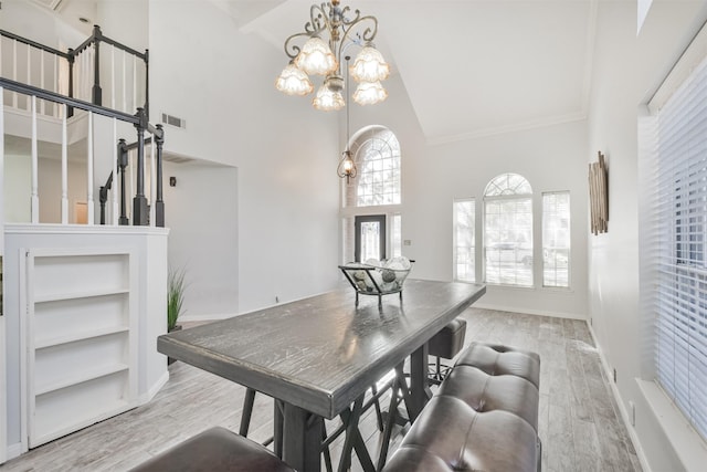 dining room featuring a notable chandelier, high vaulted ceiling, and light wood-type flooring