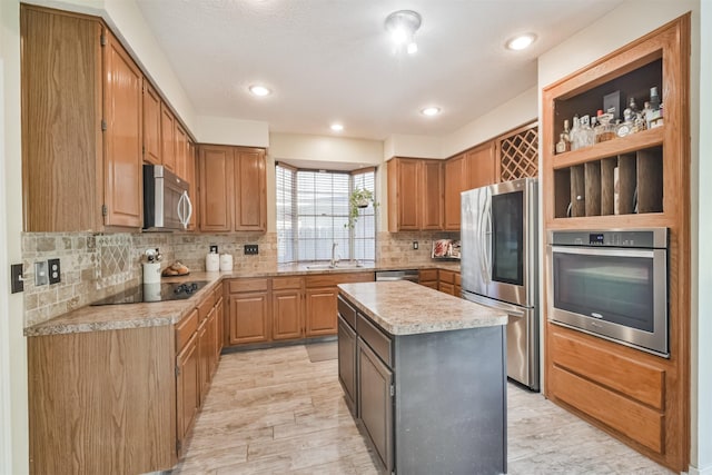 kitchen featuring a kitchen island, appliances with stainless steel finishes, tasteful backsplash, sink, and light wood-type flooring