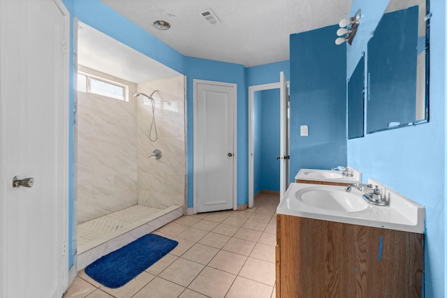 bathroom featuring tile patterned flooring, a textured ceiling, vanity, and tiled shower