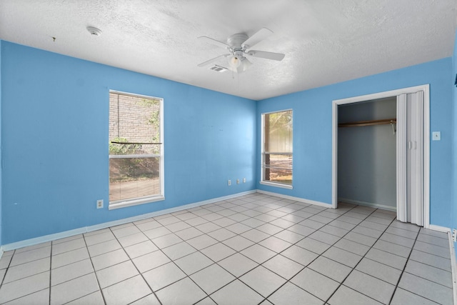 unfurnished bedroom with ceiling fan, a closet, light tile patterned floors, and a textured ceiling