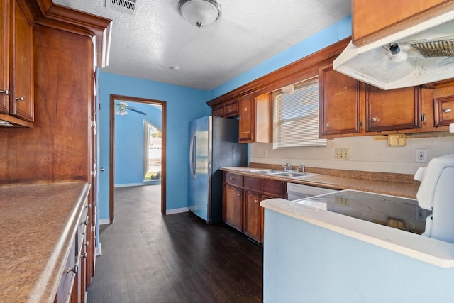 kitchen featuring dark wood-type flooring, extractor fan, sink, a textured ceiling, and stainless steel refrigerator