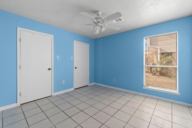 unfurnished room with ceiling fan, light tile patterned flooring, and a textured ceiling