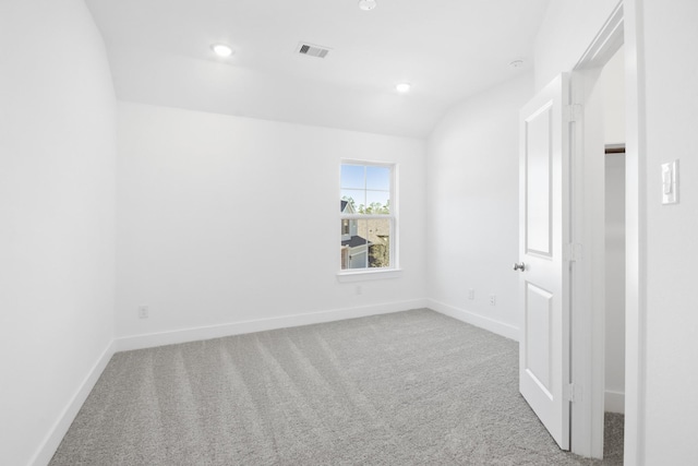 carpeted empty room featuring vaulted ceiling