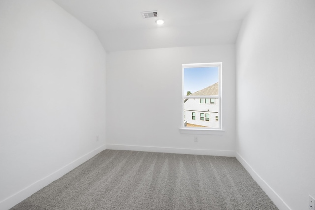 carpeted spare room featuring lofted ceiling