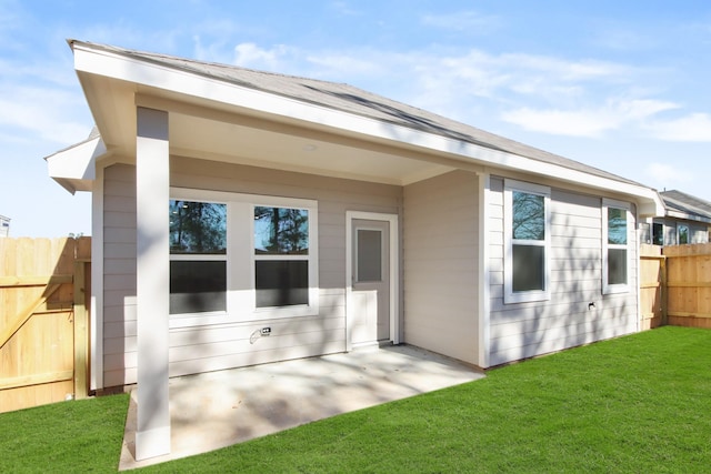 rear view of house featuring a lawn and a patio