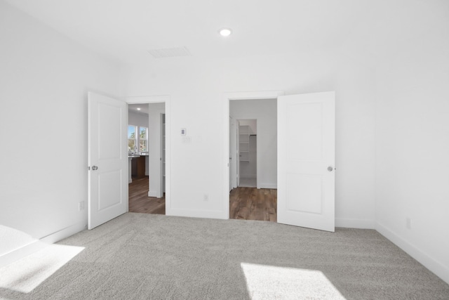 unfurnished bedroom featuring carpet floors, a spacious closet, and a closet