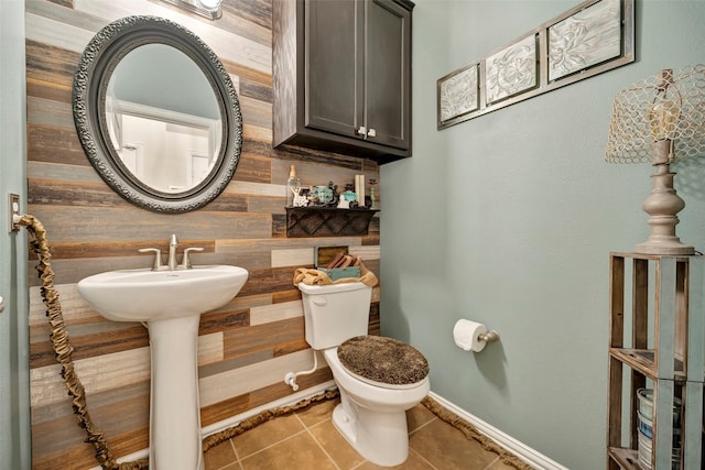 bathroom featuring tile patterned floors, wooden walls, and toilet