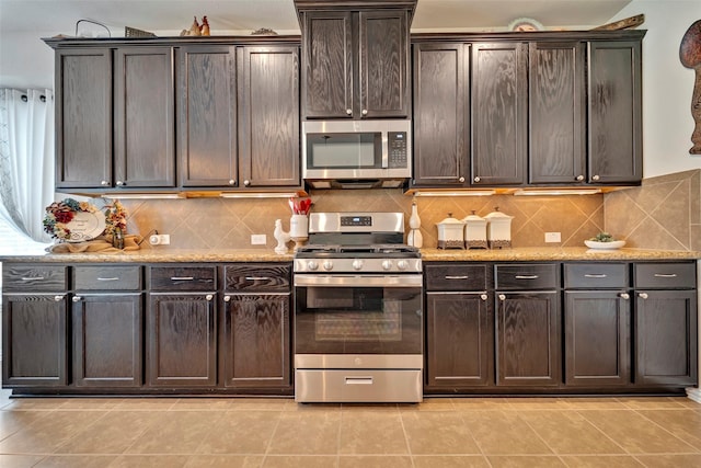 kitchen featuring dark brown cabinets, light tile patterned floors, and appliances with stainless steel finishes