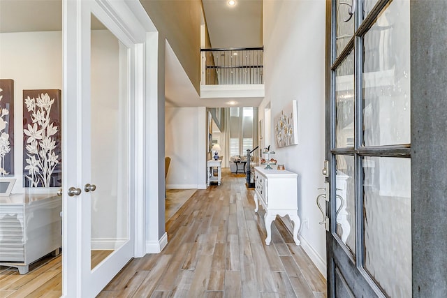 entrance foyer featuring french doors, light hardwood / wood-style flooring, and a high ceiling