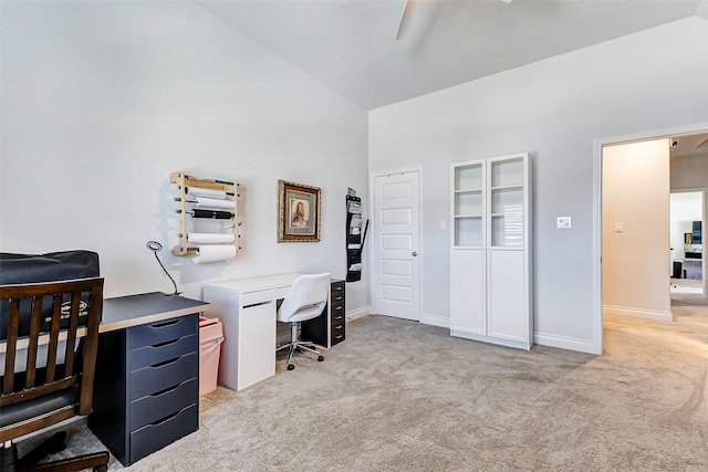 carpeted home office with built in shelves and high vaulted ceiling