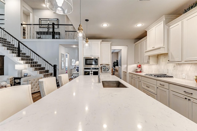 kitchen with light stone countertops, sink, pendant lighting, white cabinets, and stainless steel gas stovetop