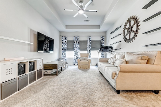 living room with carpet flooring, a tray ceiling, and ceiling fan