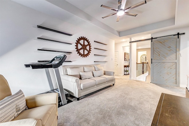 carpeted living room with a barn door, a raised ceiling, and ceiling fan