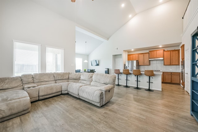 living room featuring light wood-type flooring, high vaulted ceiling, and ceiling fan