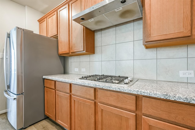 kitchen featuring decorative backsplash, appliances with stainless steel finishes, light stone counters, and ventilation hood