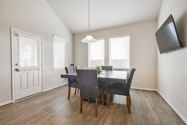 dining room with light wood-type flooring and vaulted ceiling