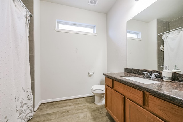 bathroom with hardwood / wood-style floors, vanity, a healthy amount of sunlight, and toilet