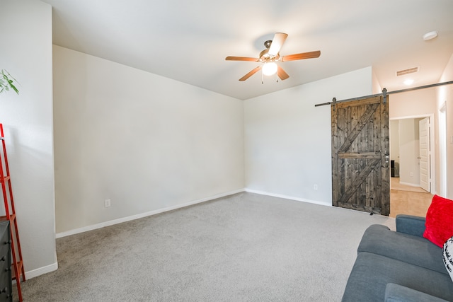 living room featuring carpet flooring, ceiling fan, and a barn door