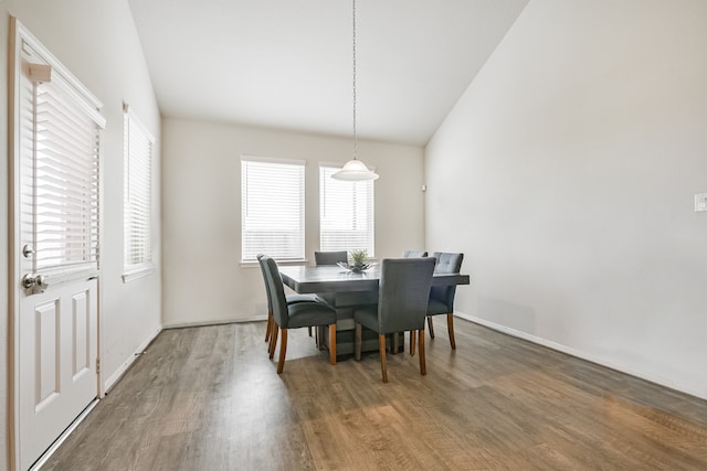 dining area with hardwood / wood-style flooring, a wealth of natural light, and vaulted ceiling