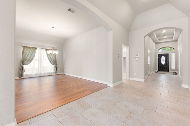 tiled entrance foyer featuring vaulted ceiling, a chandelier, and a wealth of natural light