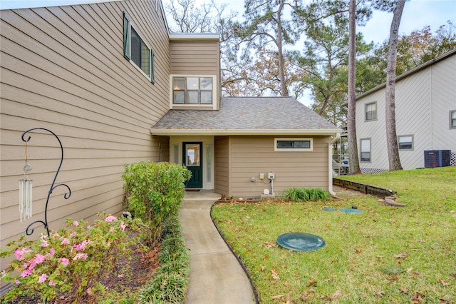 entrance to property featuring a lawn and central air condition unit