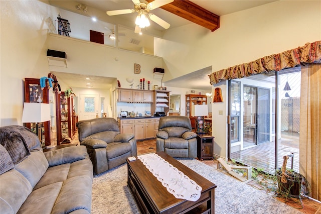 living room featuring ceiling fan, beam ceiling, and a high ceiling